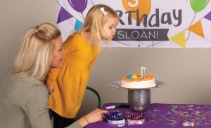 mother and child blowing out candles at birthday party