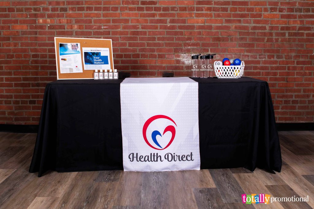 trade show booth display with a custom table runner and personalized promotional giveaways