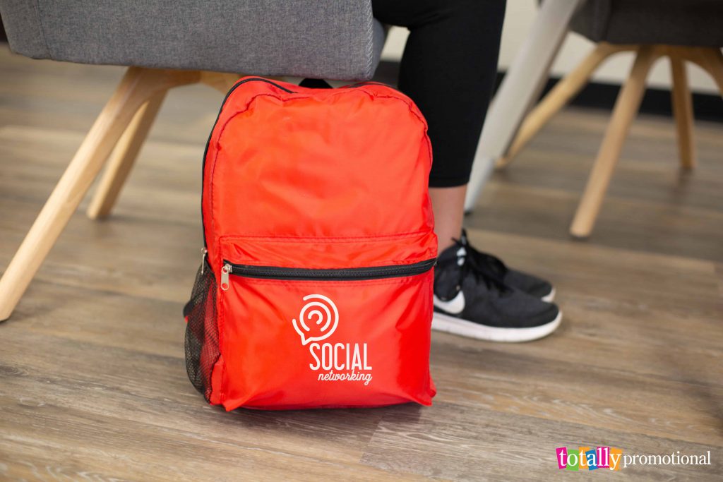 customized red backpack on the floor by a chair