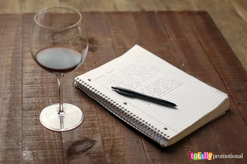 wine glass with notebook and pen