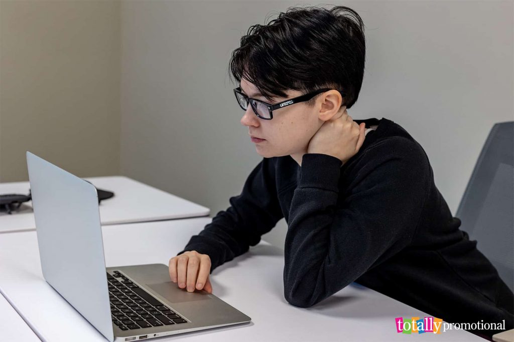 person wearing blue blocker glasses while looking at a laptop