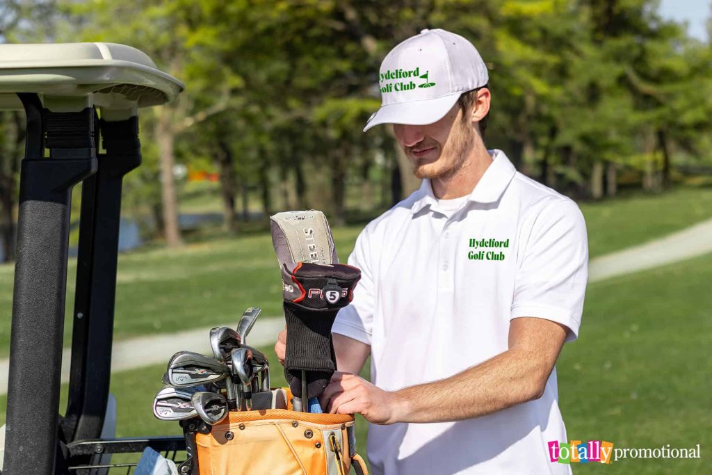 man with golf clubs and a golf cart wearing customized apparel
