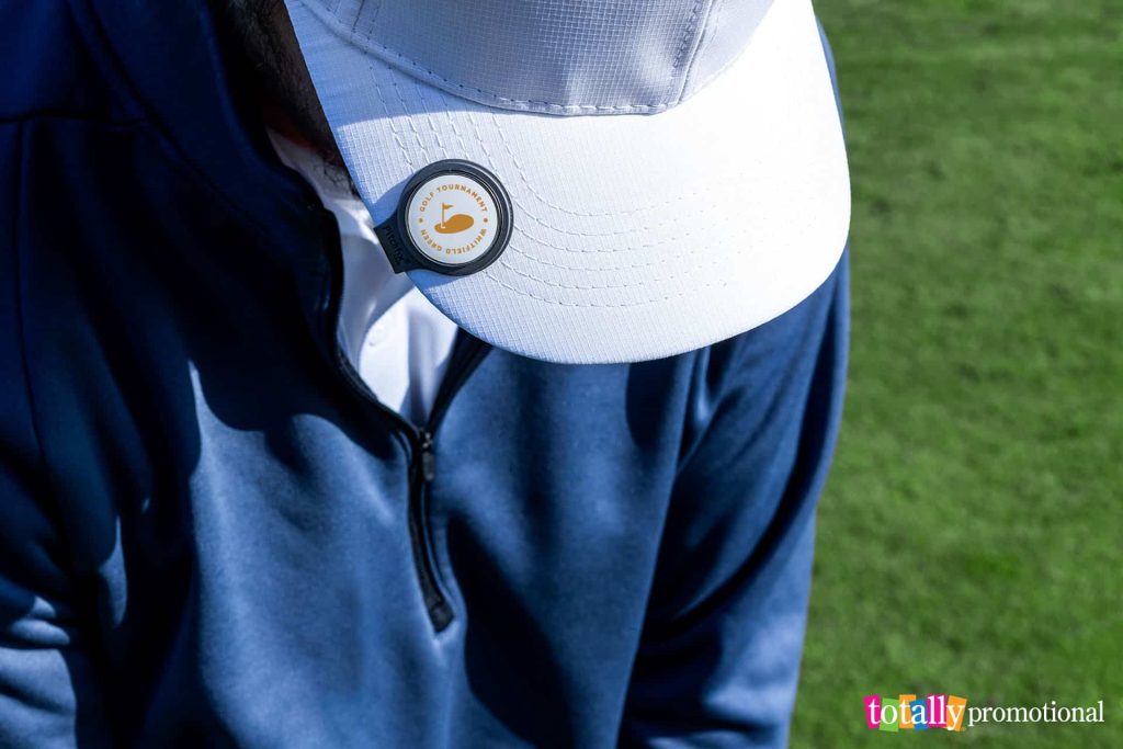 man playing golf with a customized ball marker on his hat
