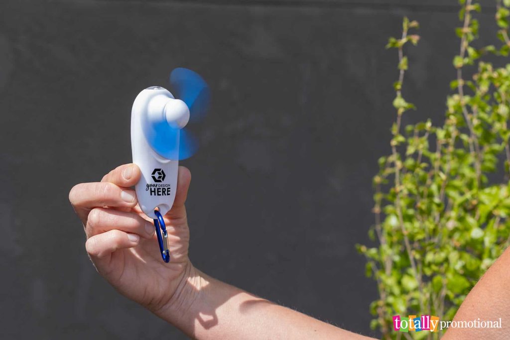 person holding a customized handy breeze portable fan and light outside