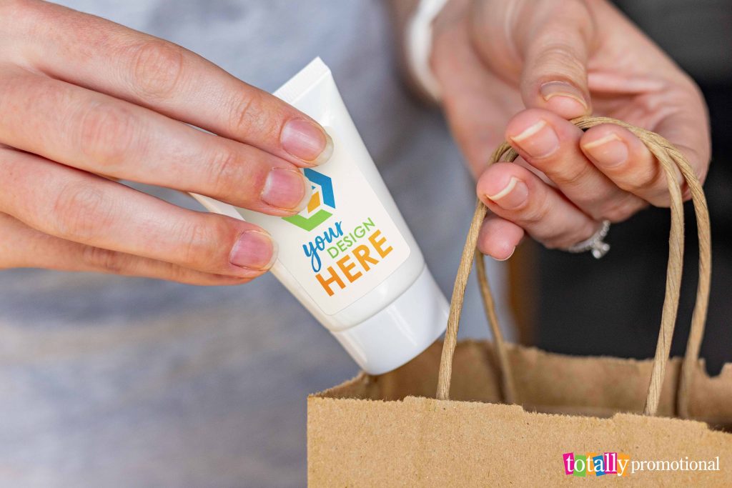 woman putting custom hand sanitizer in a gift bag