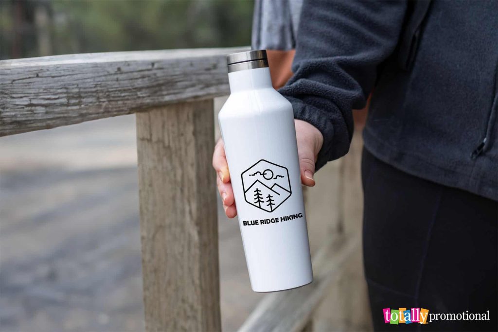 woman holding a metal customizable eco-friendly water bottle outdoors