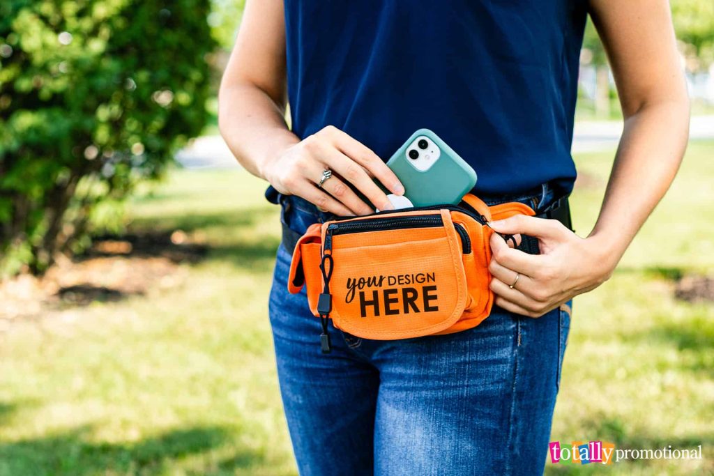 woman putting her phone into a customizable fanny pack